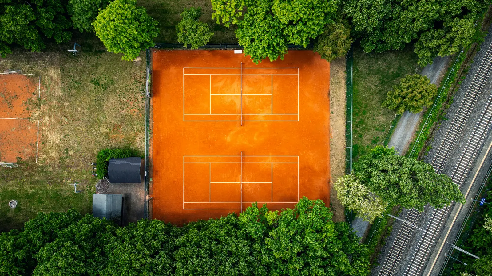 Vista aérea de canchas de tenis rodeadas de árboles